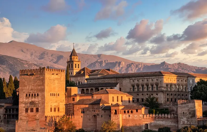 vista-de-l-alhambra-al-tramonto-con-gli-edifici-color-miele-e-le-montagne-dietro-rosate