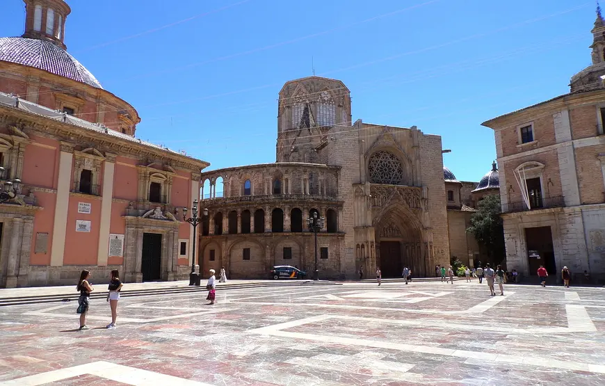 ampio-piazzale-con-dei-passanti-e-sullo-sfondo-la-cattedrale-di-vakebcua-con-un-arcata-tonda-laterale-la-facciata